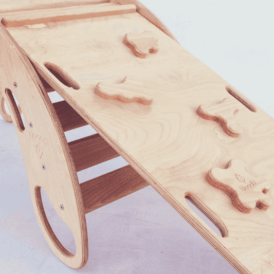 Zbliżenie na drewnianą rampę wspinaczkową z uchwytami i logo WoodU przy bujaku