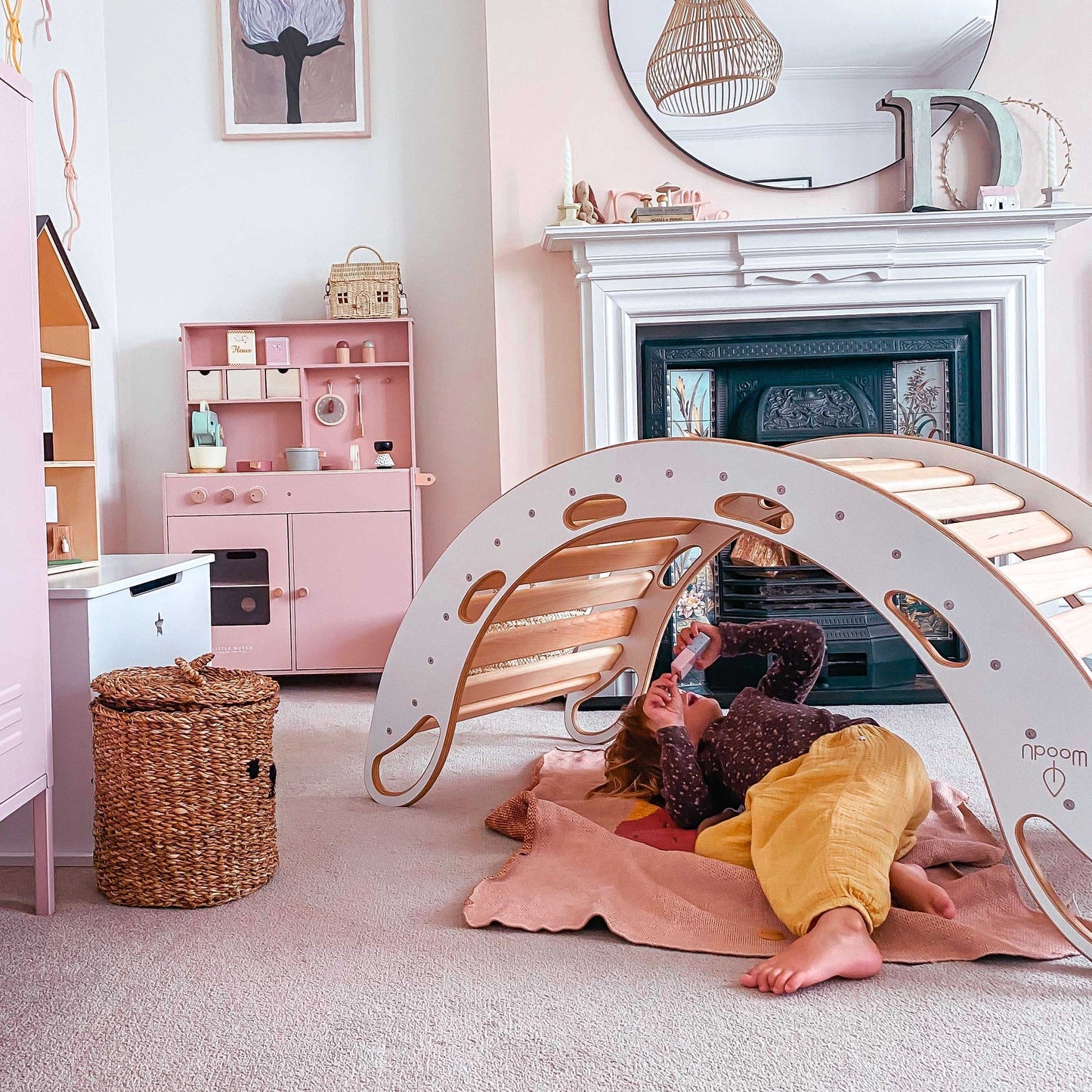 Dziecko leżące pod białym bujakiem WoodU ustawionym jako tunel w pokoju zabaw